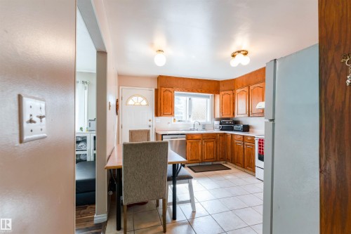 Kitchen featuring wood cabinetry, white appliances, corner sink, and tiled flooring - 4609 38A Avenue Nw, Edmonton, AB - Indoor Photo Showing Other Room