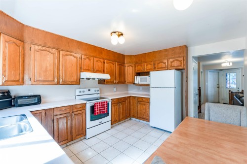 Kitchen featuring wood cabinetry, white countertops, a double-basin stainless steel sink, white tile flooring, and a white electric range - 4609 38A Avenue Nw, Edmonton, AB - Indoor Photo Showing Kitchen