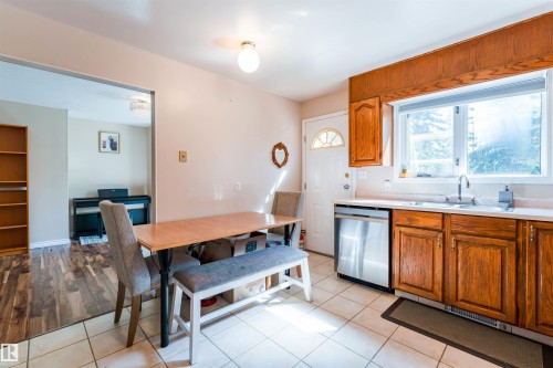 Kitchen with tiled flooring, wood cabinetry, stainless steel dishwasher, and a window above the sink - 4609 38A Avenue Nw, Edmonton, AB - Indoor