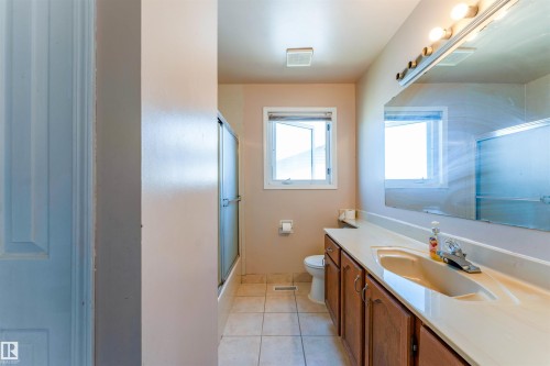 Tiled bathroom flooring with a single vanity, integrated sink, and an expansive wall mirror - 4609 38A Avenue Nw, Edmonton, AB - Indoor Photo Showing Bathroom