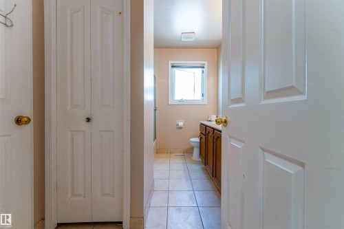 Bathroom featuring a wood-finish vanity with a light-toned countertop, a window, and tiled flooring - 4609 38A Avenue Nw, Edmonton, AB - Indoor Photo Showing Other Room