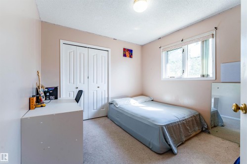 Room featuring a window, neutral-toned carpet, and a built-in closet with bifold doors - 4609 38A Avenue Nw, Edmonton, AB - Indoor Photo Showing Bedroom