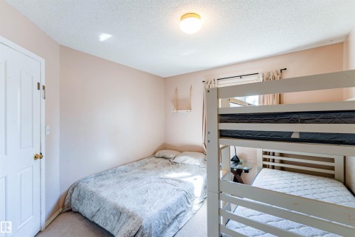 Light-colored carpeted flooring, wall-mounted light fixture, white interior door with brass hardware, and a window with curtain rod - 4609 38A Avenue Nw, Edmonton, AB - Indoor Photo Showing Bedroom
