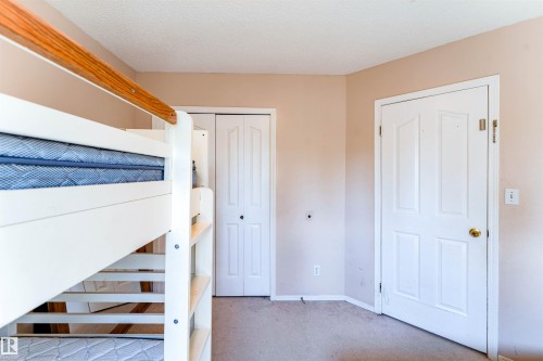 Soft neutral wall color, carpeted flooring, white paneled door, and white bi-fold closet doors - 4609 38A Avenue Nw, Edmonton, AB - Indoor Photo Showing Other Room