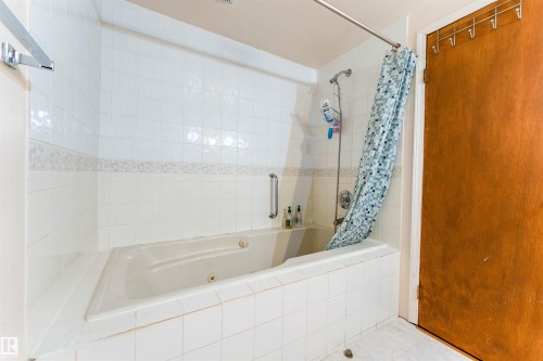 White tiled bath surround with decorative accent tile - 4609 38A Avenue Nw, Edmonton, AB - Indoor Photo Showing Bathroom