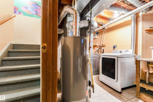 Carpeted stairs with a natural wood handrail - 4609 38A Avenue Nw, Edmonton, AB - Indoor Photo Showing Laundry Room