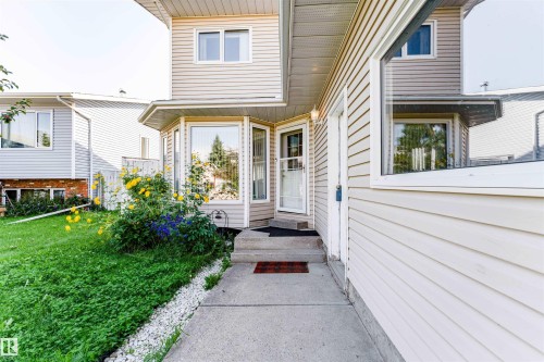 Siding exterior with multiple windows, concrete walkway, and landscaped garden beds - 4609 38A Avenue Nw, Edmonton, AB - Outdoor With Exterior