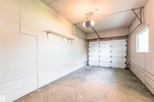 Garage with concrete flooring, automatic garage door opener, and a single window - 4609 38A Avenue Nw, Edmonton, AB - Indoor Photo Showing Garage