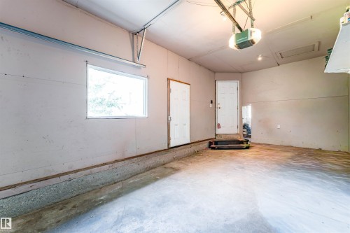Concrete flooring, overhead garage door mechanism, exterior window, white paneled door, additional white door - 4609 38A Avenue Nw, Edmonton, AB - Indoor Photo Showing Other Room