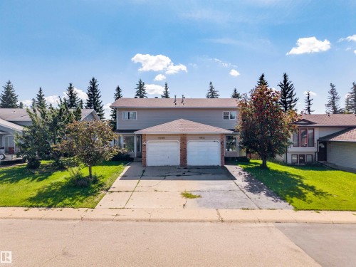 Duplex property featuring two attached garages, a pitched roofline, and front landscaping with mature trees and green lawns - 4609 38A Avenue Nw, Edmonton, AB - Outdoor With Facade
