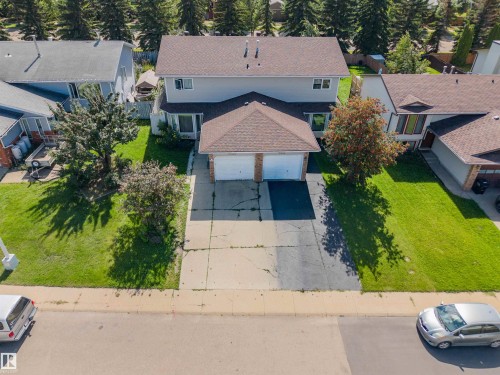 Two-story residence featuring a two-car garage with stone detailing, a paved driveway, and established front yard landscaping with mature trees - 4609 38A Avenue Nw, Edmonton, AB - Outdoor