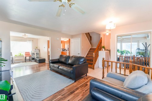 Expansive living area featuring wood-finish flooring, a ceiling fan, and a prominent staircase with wood railings - 4609 38A Avenue Nw, Edmonton, AB - Indoor Photo Showing Living Room