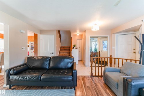 Wood-finish flooring, white paneled doors, staircase with wood risers and treads, neutral wall paint, and overhead lighting - 4609 38A Avenue Nw, Edmonton, AB - Indoor Photo Showing Living Room