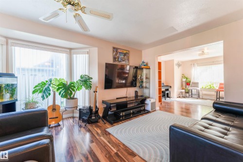 Bay window with vertical blinds, wood-finish flooring, ceiling fan with integrated lighting, and an open doorway - 4609 38A Avenue Nw, Edmonton, AB - Indoor Photo Showing Living Room