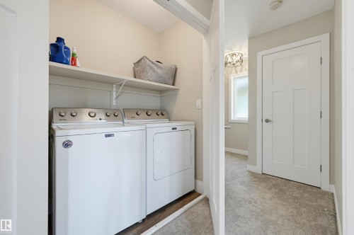 Dedicated laundry area featuring a white top-load washer and dryer set, integrated shelving, and neutral wall tones - 12219 93 Street Nw, Edmonton, AB - Indoor Photo Showing Laundry Room
