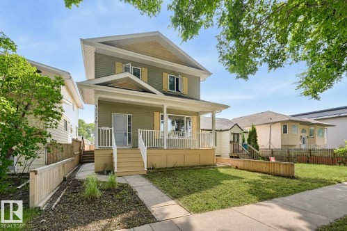 Two-story residential exterior featuring sage green siding, contrasting yellow shutters, and a covered front porch with white railings - 12219 93 Street Nw, Edmonton, AB - Outdoor With Deck Patio Veranda