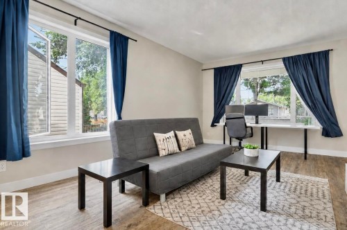Bright living area featuring wood-finish flooring, light neutral wall tones, and multiple windows - 12219 93 Street Nw, Edmonton, AB - Indoor Photo Showing Living Room