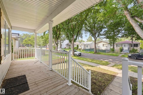 Covered front porch featuring wood-finish flooring, white railing, and columns - 12219 93 Street Nw, Edmonton, AB - Outdoor With Deck Patio Veranda