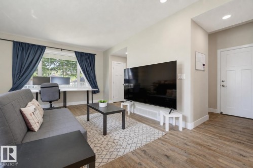 Open-concept living space with wood-finish flooring, recessed lighting, and a white paneled entry door - 12219 93 Street Nw, Edmonton, AB - Indoor Photo Showing Living Room