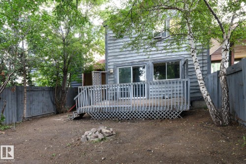 Rear exterior with wood siding, a raised wood deck, sliding glass doors, and mature trees - 5511 92C Avenue Nw, Edmonton, AB - Outdoor With Deck Patio Veranda