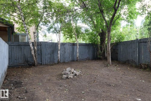 Fenced backyard with mature trees and a stone fire pit - 5511 92C Avenue Nw, Edmonton, AB - Outdoor