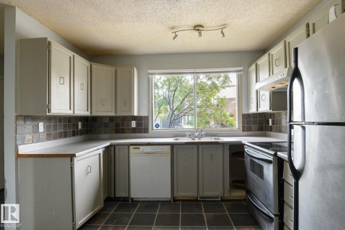 Kitchen featuring white cabinetry, a tiled backsplash, and stainless steel appliances - 5511 92C Avenue Nw, Edmonton, AB - Indoor Photo Showing Kitchen