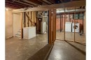 Unfinished basement space with exposed ceiling joists, concrete flooring, and built-in laundry appliances - 5511 92C Avenue Nw, Edmonton, AB  - Indoor Photo Showing Basement 