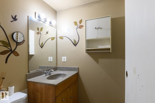 Vanity with integrated sink, wood-finish cabinetry, and stone-finish countertop - 5511 92C Avenue Nw, Edmonton, AB - Indoor Photo Showing Bathroom