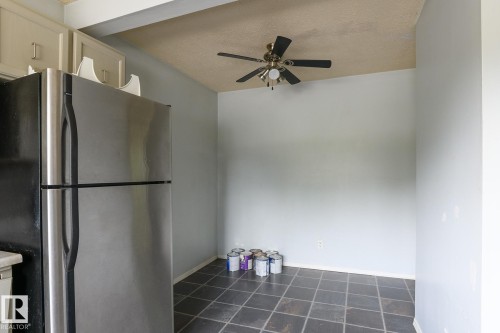 Stainless steel refrigerator, built-in cabinetry, ceiling fan with light fixture, and square tile flooring - 5511 92C Avenue Nw, Edmonton, AB - Indoor