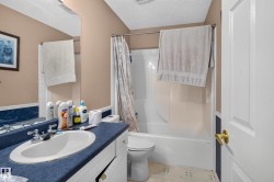 Bathroom featuring a white vanity with a single basin, a full-width mirror, and a shower-tub combination with white surround - 