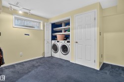 Laundry area with front-loading washer and dryer, built-in shelving, track lighting, and blue carpeting - 