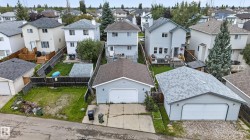 Two-story residence featuring a detached garage with a white overhead door and a second detached garage with a white overhead door - 