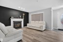 Wood-finish flooring, recessed ceiling lighting, fireplace with mantel and stone-finish surround, front entry door with decorative glass, and tiled entryway - 3755 20 Street Nw, Edmonton, AB  - Indoor With Fireplace 
