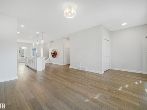 Open-concept living space featuring wood-finish flooring, recessed lighting, and a kitchen island with pendant lighting - 203 Cavanagh Common Sw, Edmonton, AB - Indoor Photo Showing Other Room
