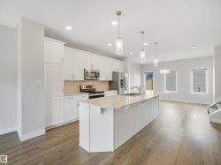 Gourmet kitchen with white cabinetry, light-toned countertops, tile backsplash, and stainless steel appliances - 