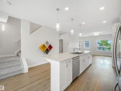 Kitchen island featuring a double-basin sink, stainless steel dishwasher, and white cabinetry - 