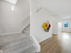 Carpeted staircase with white handrail, recessed wall lighting, and wood-finish flooring - 