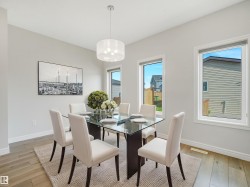 Recessed white walls, wood-finish flooring, two large windows, and a drum pendant light fixture - 