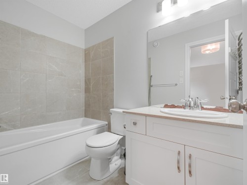 White vanity with cabinet storage, integrated sink, and chrome faucet - 203 Cavanagh Common Sw, Edmonton, AB - Indoor Photo Showing Bathroom