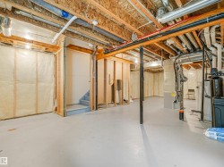 Unfinished basement offering exposed wood framing, insulated walls, concrete flooring, and visible utility systems - 