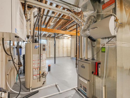 Unfinished basement space featuring a water heater, furnace, and exposed ceiling joists - 203 Cavanagh Common Sw, Edmonton, AB - Indoor Photo Showing Basement