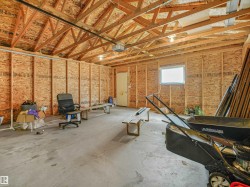 Spacious garage with exposed wood trusses, concrete flooring, and a single window - 
