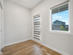 Wood-finish flooring, white trim, and a frosted glass door with horizontal banding - 