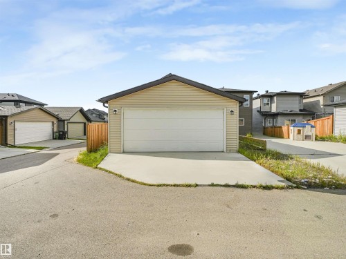 Detached two-car garage with beige horizontal siding and black shingles - 203 Cavanagh Common Sw, Edmonton, AB - Outdoor