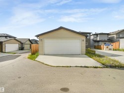 Detached two-car garage with beige horizontal siding and black shingles - 