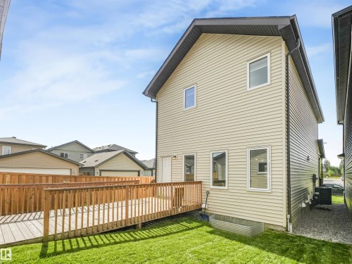 Exterior featuring beige horizontal siding, white-framed windows, and a black shingled roof - 203 Cavanagh Common Sw, Edmonton, AB - Outdoor With Exterior