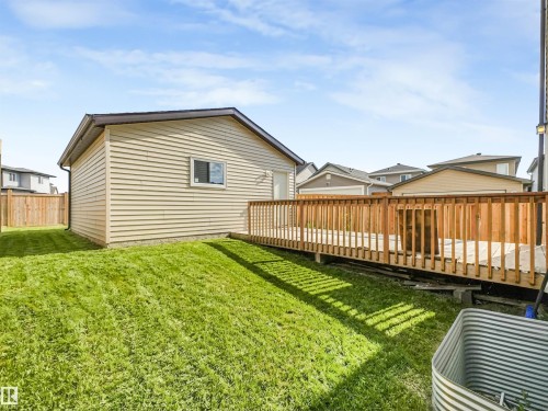 Expansive backyard featuring a manicured lawn, a large wood deck, and a detached structure with siding - 203 Cavanagh Common Sw, Edmonton, AB - Outdoor With Deck Patio Veranda With Exterior