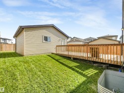 Expansive backyard featuring a manicured lawn, a large wood deck, and a detached structure with siding - 