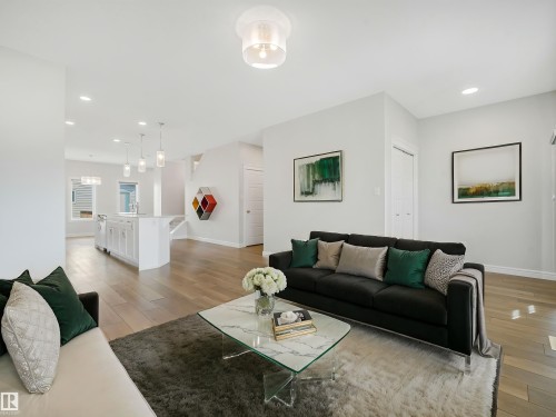 Open-concept living space featuring wood-finish flooring, recessed lighting, and a kitchen island with pendant lighting - 203 Cavanagh Common Sw, Edmonton, AB - Indoor Photo Showing Living Room