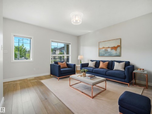 Wood-finish flooring, multiple windows, and a flush mount ceiling light fixture - 203 Cavanagh Common Sw, Edmonton, AB - Indoor Photo Showing Living Room